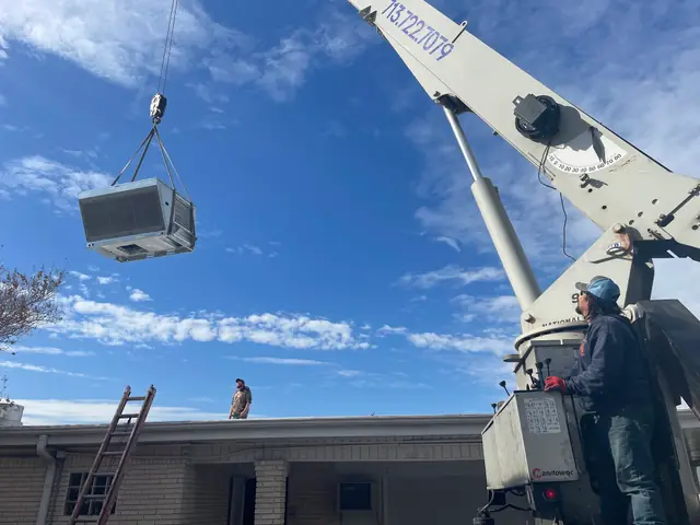A commercial rooftop unit lifted into place by crane